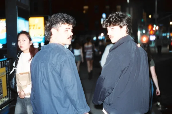 Two friends looking back toward the camera on a city street at night.